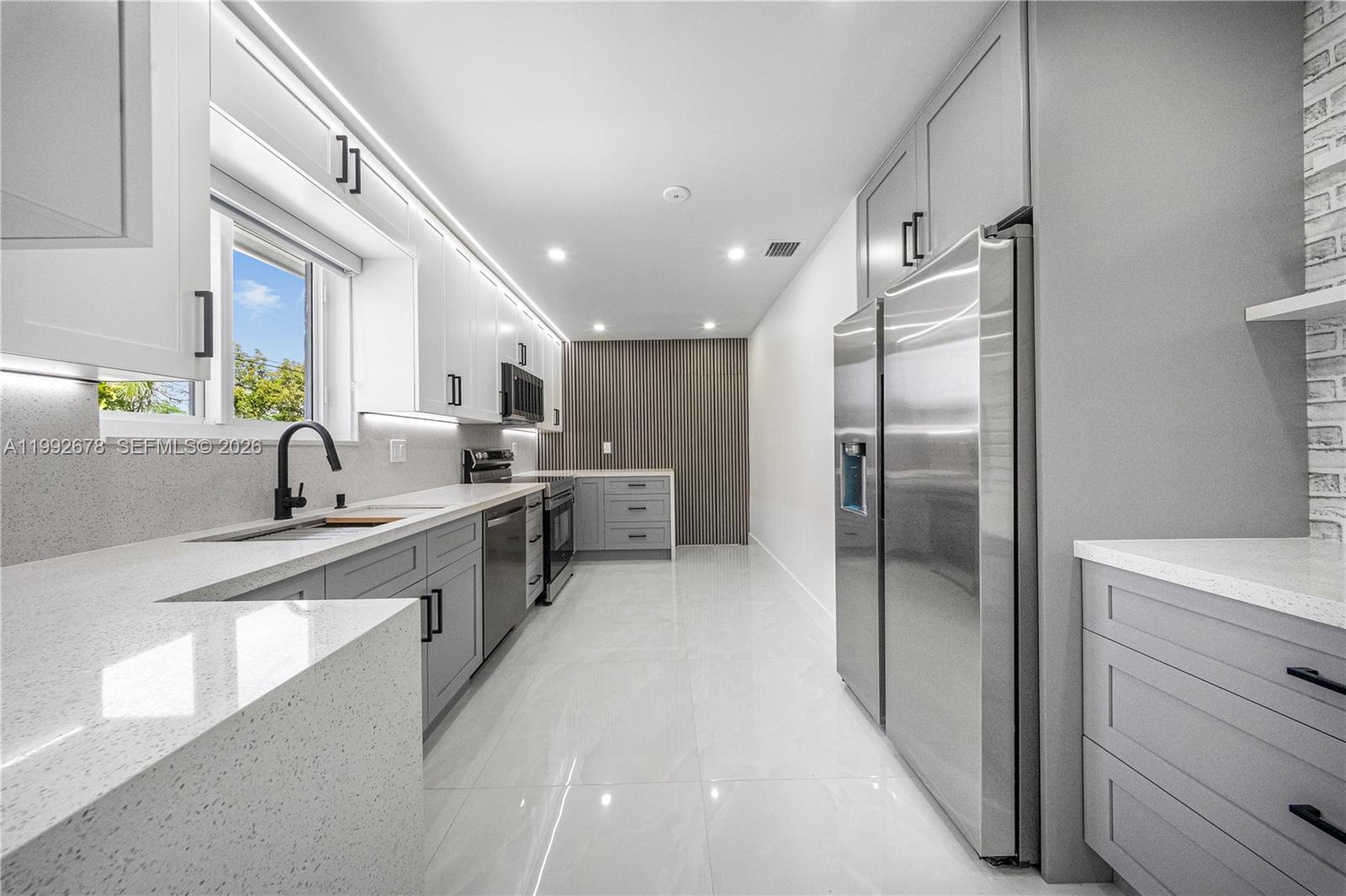 A modern kitchen features white upper cabinets, gray lower cabinets, stainless steel appliances, and quartz countertops — 17860 SW 110th Ct, Miami FL 33157, MIAMI, FL
