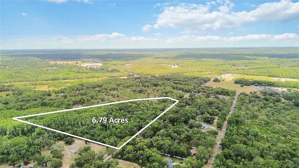 An aerial view shows a triangular plot of land outlined in white amidst wooded surroundings — 5018 N ANDRI DRIVE, CRYSTAL RIVER, FL
