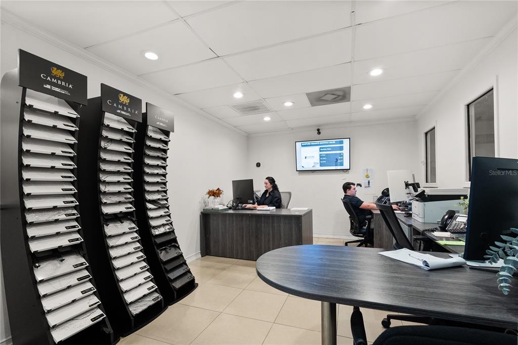 An office space features two Cambria stone sample display racks, desks, and two employees working — 1410-1430 TROPIC PARK DRIVE UNIT 1410-1430, SANFORD, FL