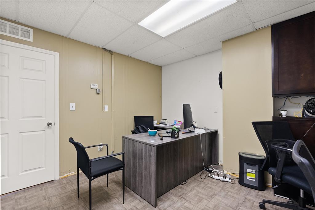 An office space features a gray desk, two black chairs, and tan paneled walls — 1410-1430 TROPIC PARK DRIVE UNIT 1410-1430, SANFORD, FL