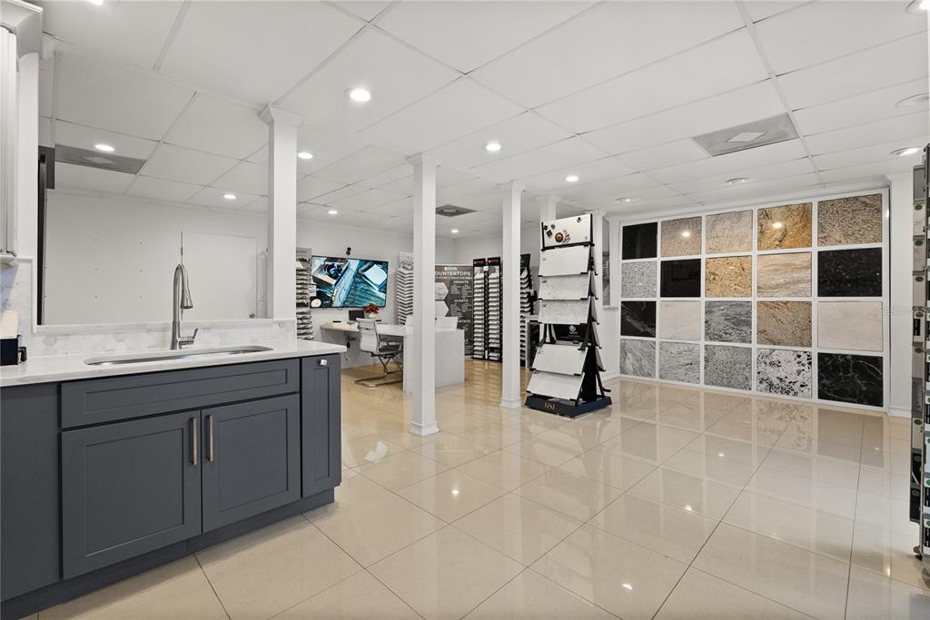 A showroom features a dark gray kitchen island, a tile sample display, and stone wall samples — 1410-1430 TROPIC PARK DRIVE UNIT 1410-1430, SANFORD, FL
