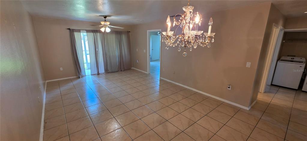 A dining area with tile flooring, a crystal chandelier, and a sliding glass door — 13313 FAIRWAY GLEN DRIVE UNIT 104, ORLANDO, FL