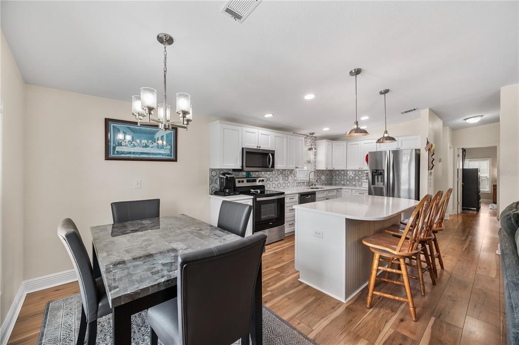 A kitchen with white cabinets, a central island, and an adjacent dining area with seating — 1502 LONGBOW DRIVE, LAKELAND, FL