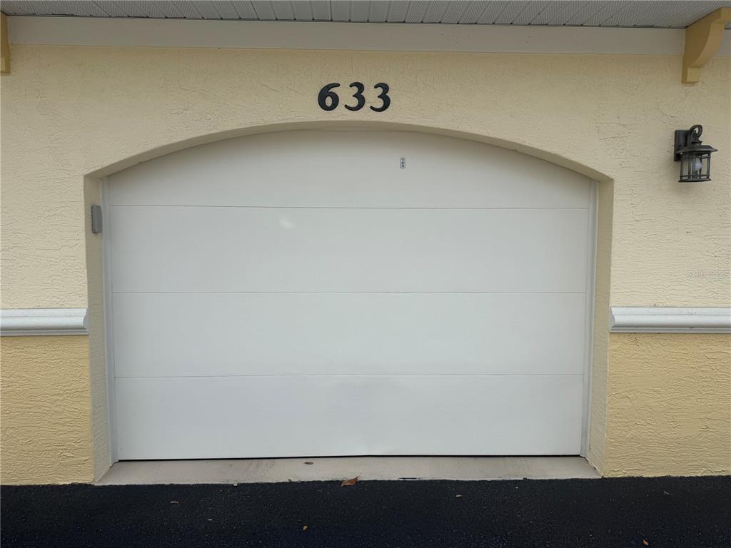 A white garage door with the number 633 above it on a beige stucco building — 600 GARDENS EDGE DRIVE UNIT 633, VENICE, FL