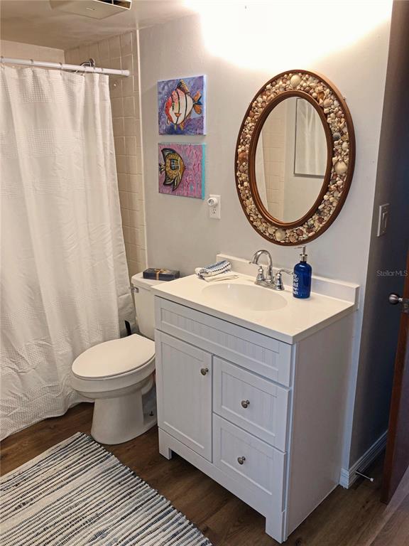 A bathroom features a white vanity, a shell-framed oval mirror, and a shower with a curtain — 3006 CARING WAY UNIT 409, PORT CHARLOTTE, FL