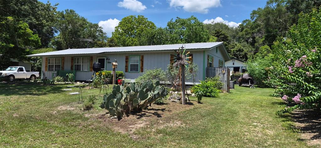 A single-story house with light-colored siding and a metal roof sits on a grassy lot — 17144 NW 239TH TERRACE, HIGH SPRINGS, FL