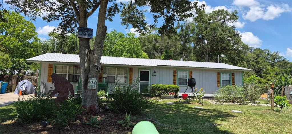A single-story house with a metal roof and a Bigfoot cutout in the front yard — 17144 NW 239TH TERRACE, HIGH SPRINGS, FL