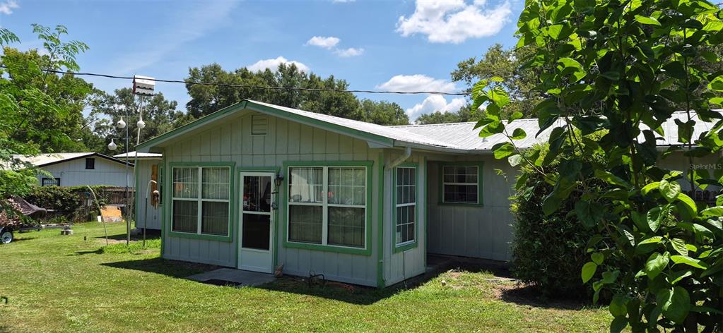 The exterior of a light-colored, single-story house with green trim and a metal roof — 17144 NW 239TH TERRACE, HIGH SPRINGS, FL