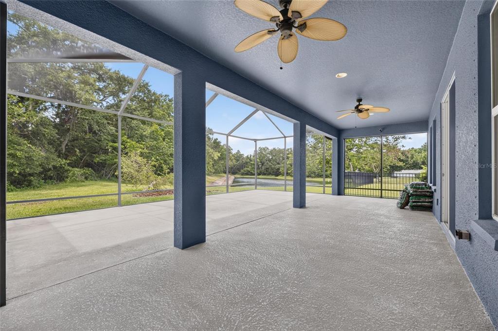 A covered patio with a concrete floor, ceiling fans, and a screened-in view of a pond — 3506 WICKET FIELD ROAD, LUTZ, FL