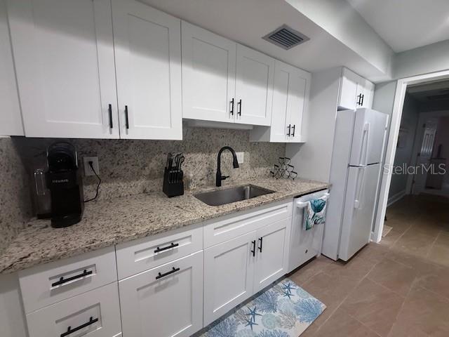 A kitchen features white cabinets, granite countertops, a stainless steel sink, and a white refrigerator — 143 WHISPERING SANDS DRIVE UNIT N/A, SARASOTA, FL