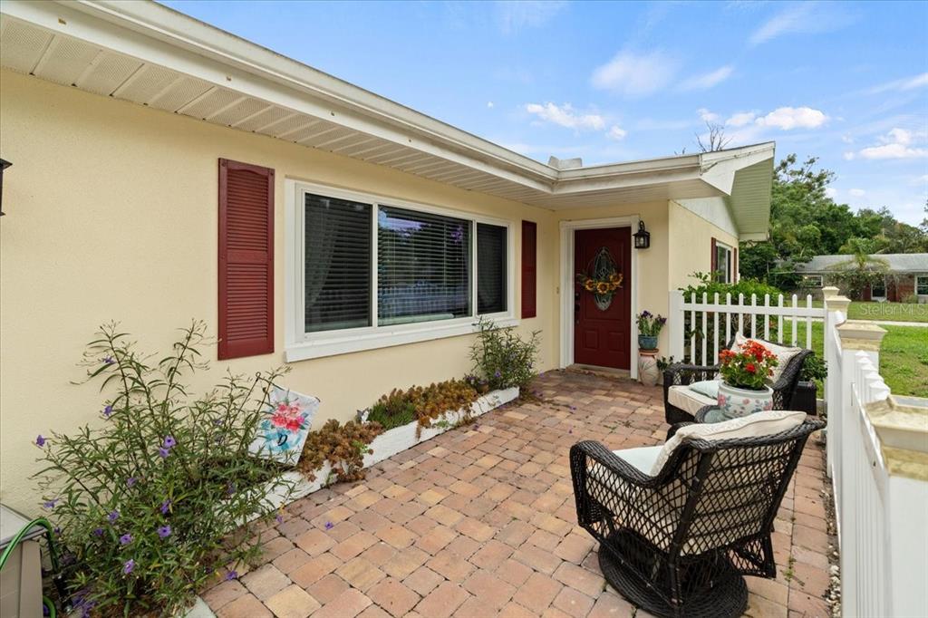 A paved patio sits in front of a yellow house with a red door — 1560 BEL KEENE DRIVE, CLEARWATER, FL