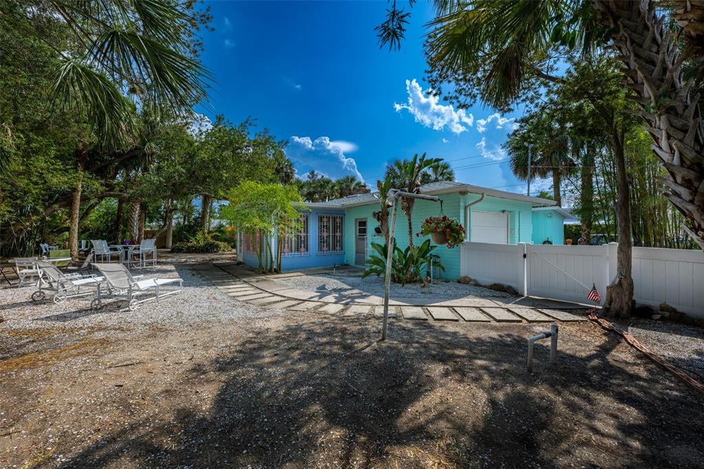A light blue house with a white fence and patio furniture in a gravel yard — 705 N PENINSULA AVENUE, NEW SMYRNA BEACH, FL