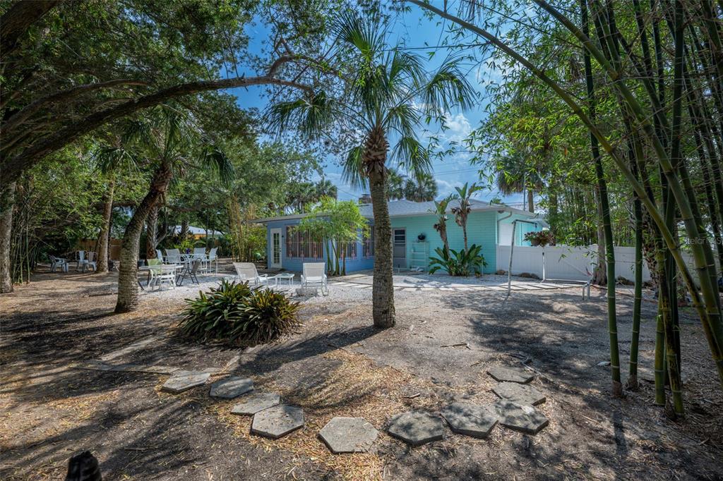 A light blue house sits in a backyard with palm trees, bamboo, and patio furniture — 705 N PENINSULA AVENUE, NEW SMYRNA BEACH, FL