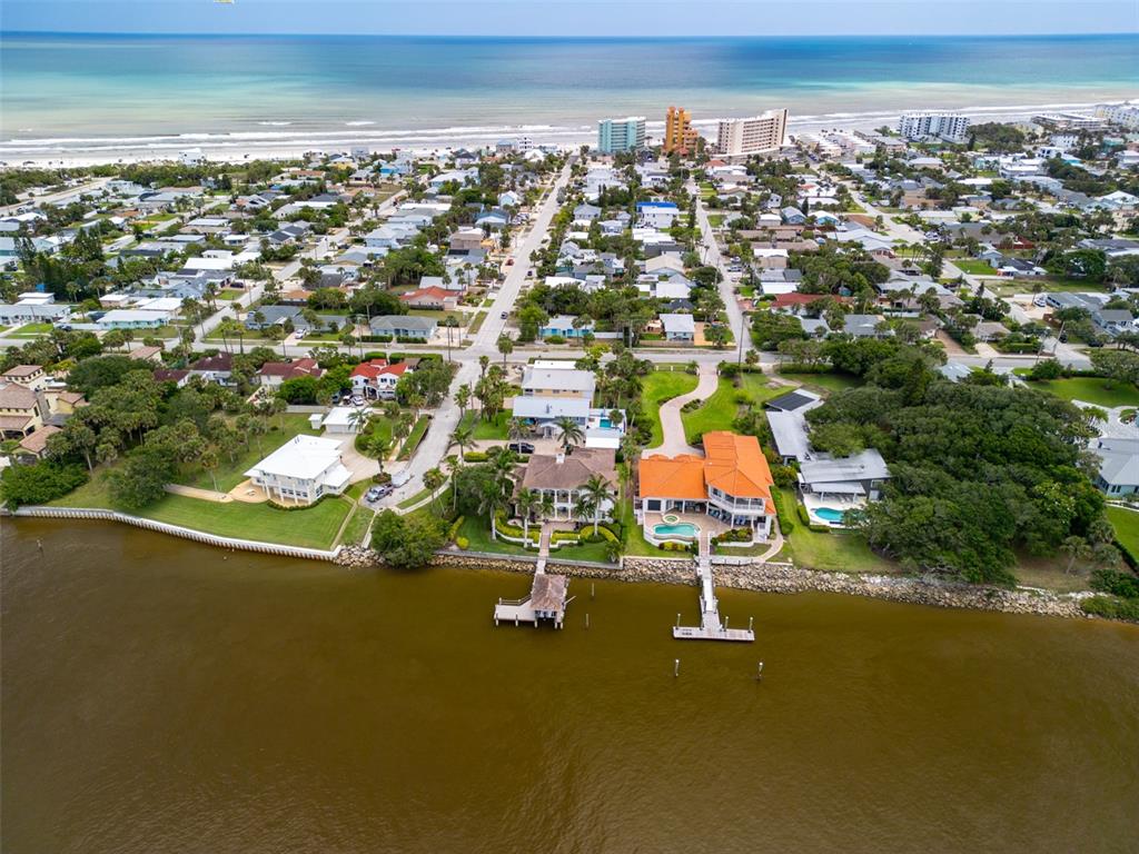 An aerial view of waterfront homes with private docks along a river near the ocean — 705 N PENINSULA AVENUE, NEW SMYRNA BEACH, FL