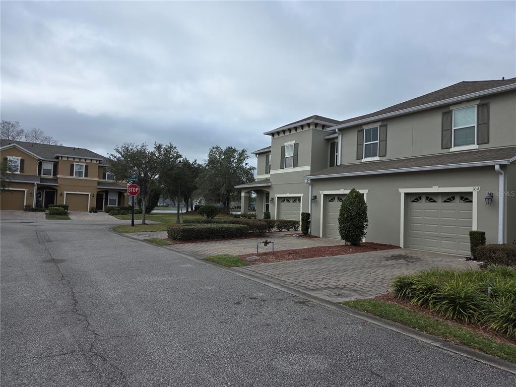 A view of a residential street featuring two-story townhomes with paved driveways and garages — 104 KELLY THOMAS WAY, DAYTONA BEACH, FL
