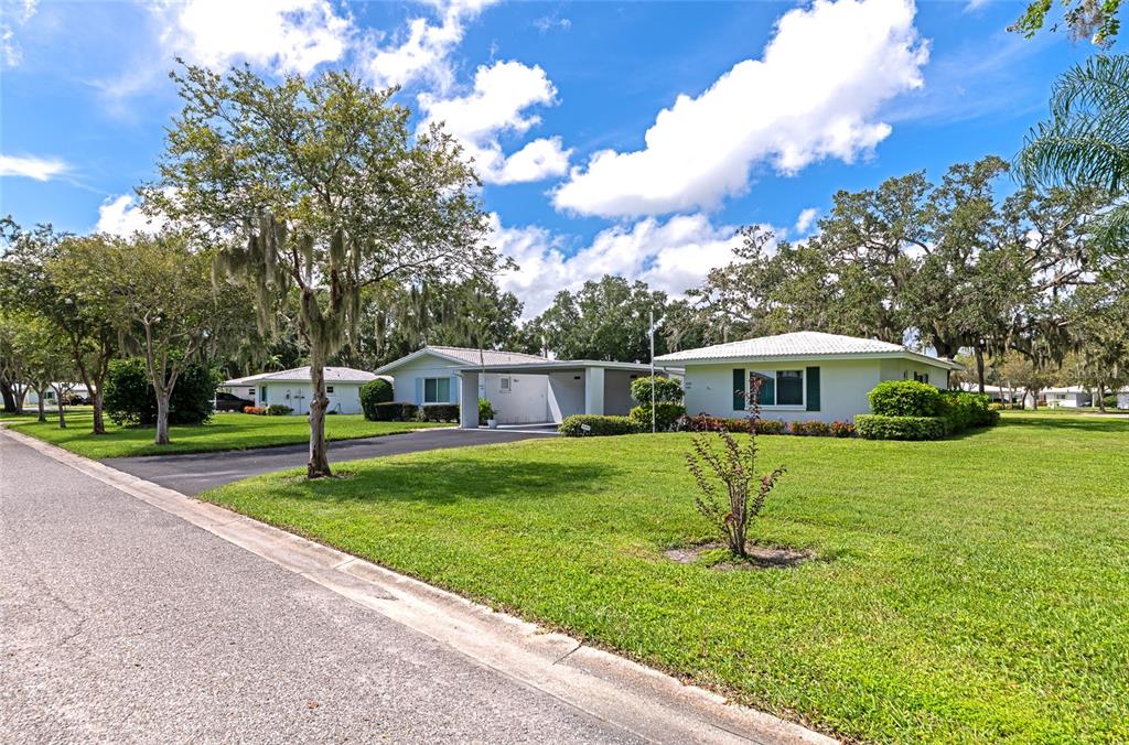 A single-story house with a carport and a large lawn under a blue sky — 4202 SCHWALBE DRIVE UNIT 89, SARASOTA, FL