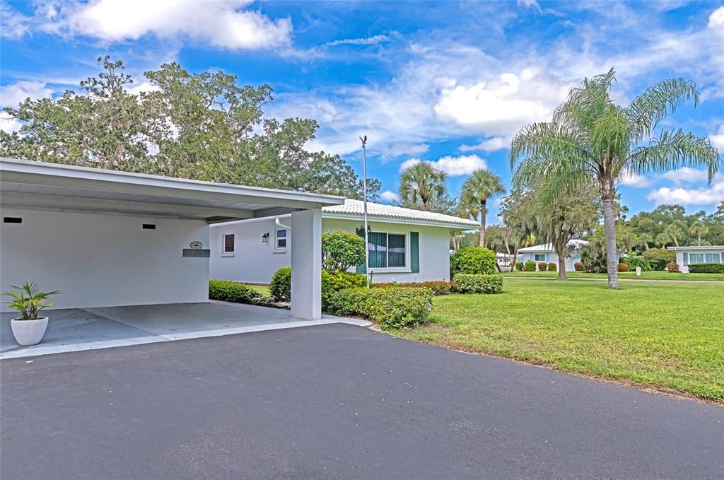 A white house with a carport and a large lawn under a blue sky — 4202 SCHWALBE DRIVE UNIT 89, SARASOTA, FL