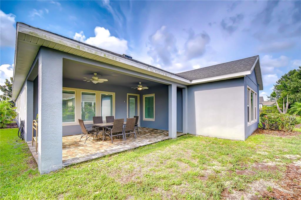 A covered patio with a paved floor and dining set attached to a gray house — 14014 SWALLOW HILL DRIVE, LITHIA, FL