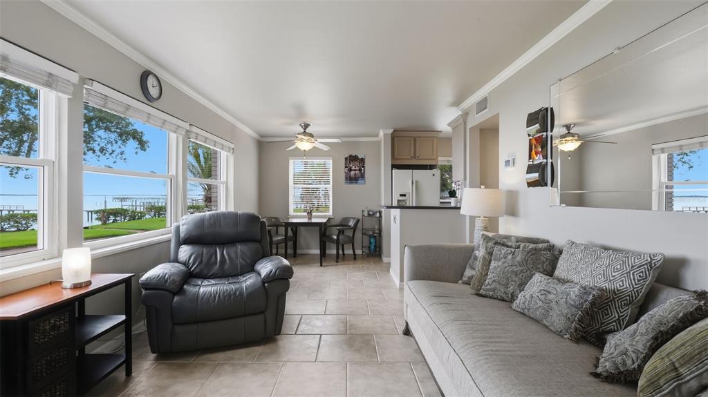 A covered patio features a brick floor, two chairs, a glass door, and waterfront views — 1101 VICTORIA DRIVE UNIT 1, DUNEDIN, FL