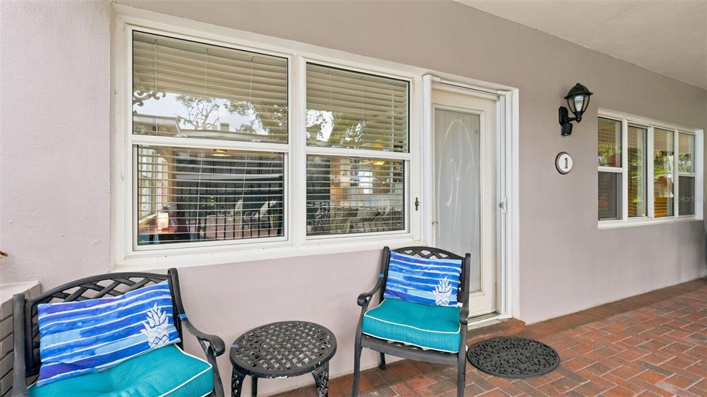 A living room with tile floors, a television, a recliner, and large windows overlooking water — 1101 VICTORIA DRIVE UNIT 1, DUNEDIN, FL