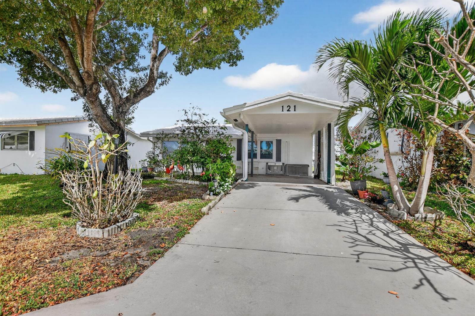 A single-story house with a concrete driveway, a carport, and a large tree in front — 121 NW 28th Court, Pompano Beach FL 33064, POMPANO BEACH, FL
