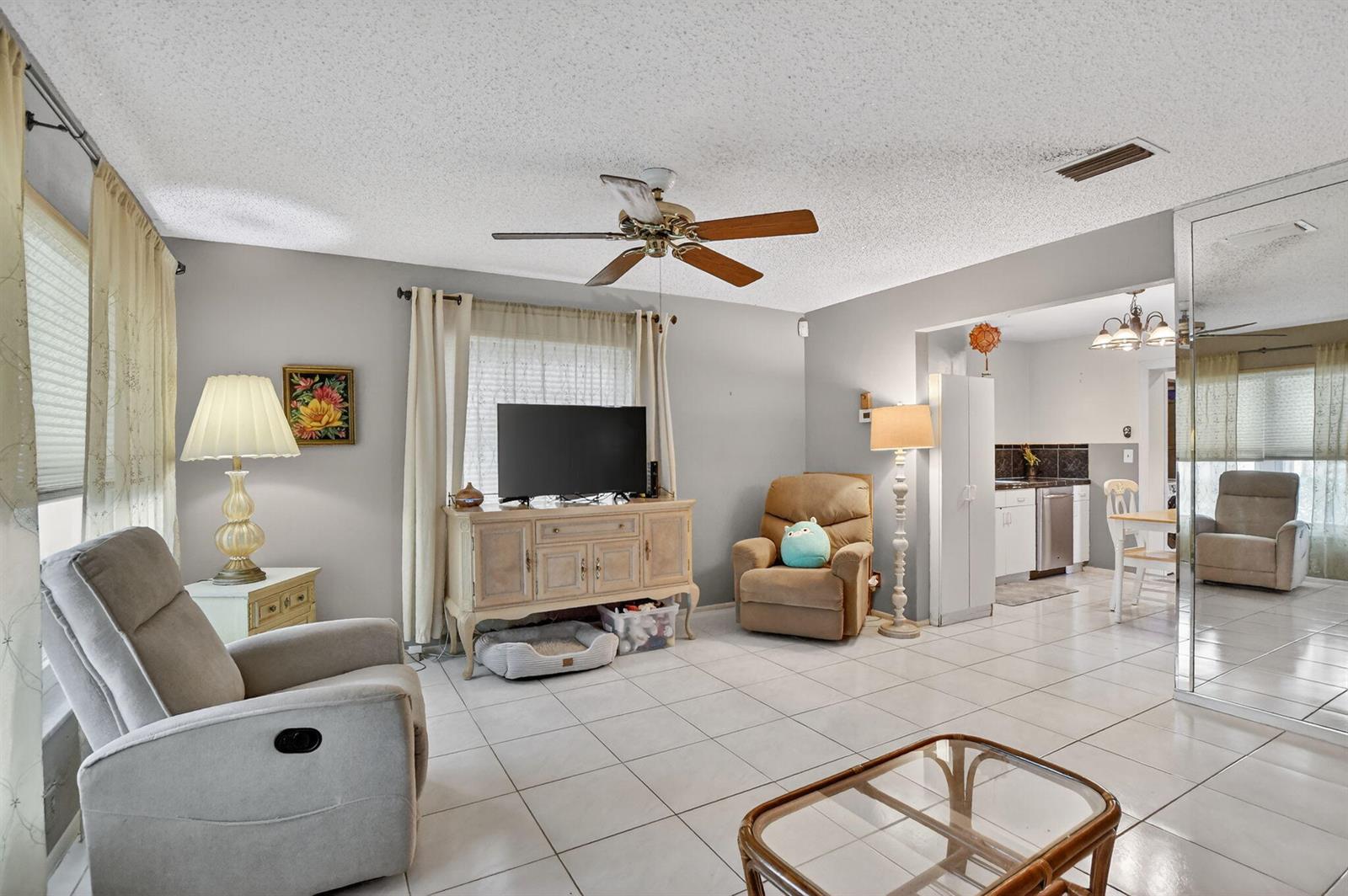 A living room with light gray walls, tile flooring, a ceiling fan, and a television console — 121 NW 28th Court, Pompano Beach FL 33064, POMPANO BEACH, FL