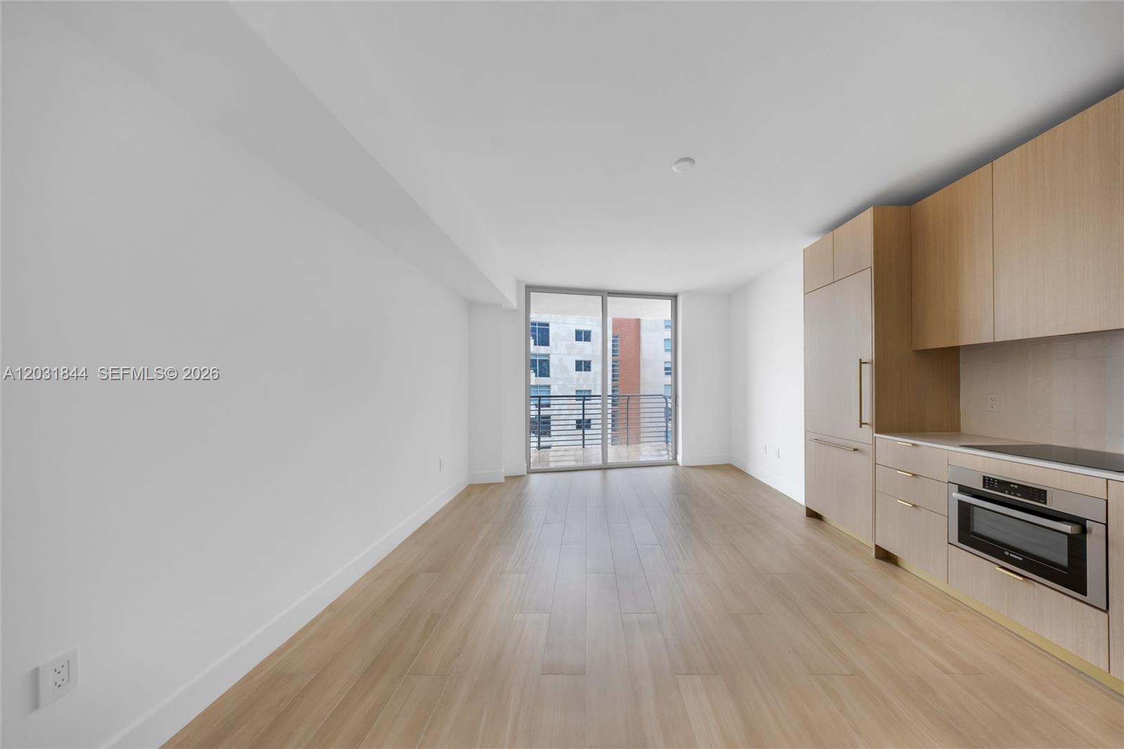 This modern kitchen and living area features light wood cabinetry, stainless appliances, and balcony access — 90 NE 32 # 1013, Miami FL 33137, MIAMI, FL