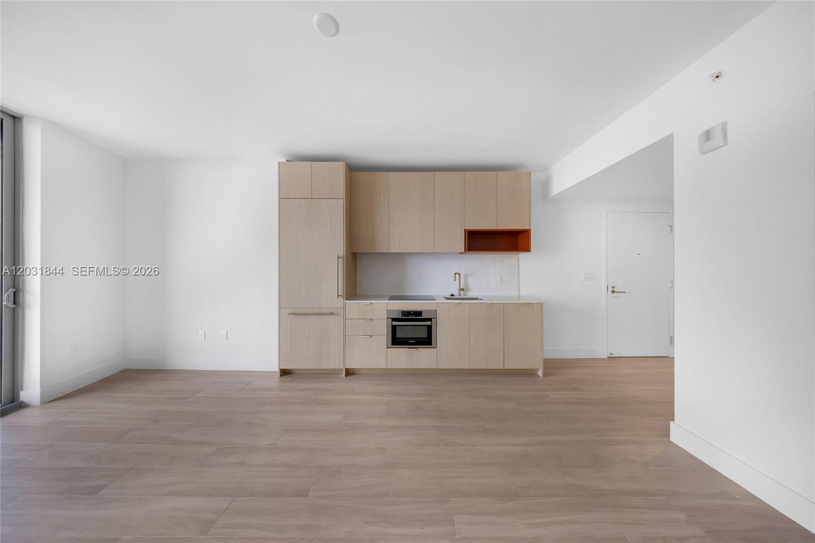 A modern kitchen with light wood cabinetry and stainless steel appliances sits in an open room — 90 NE 32 # 1013, Miami FL 33137, MIAMI, FL