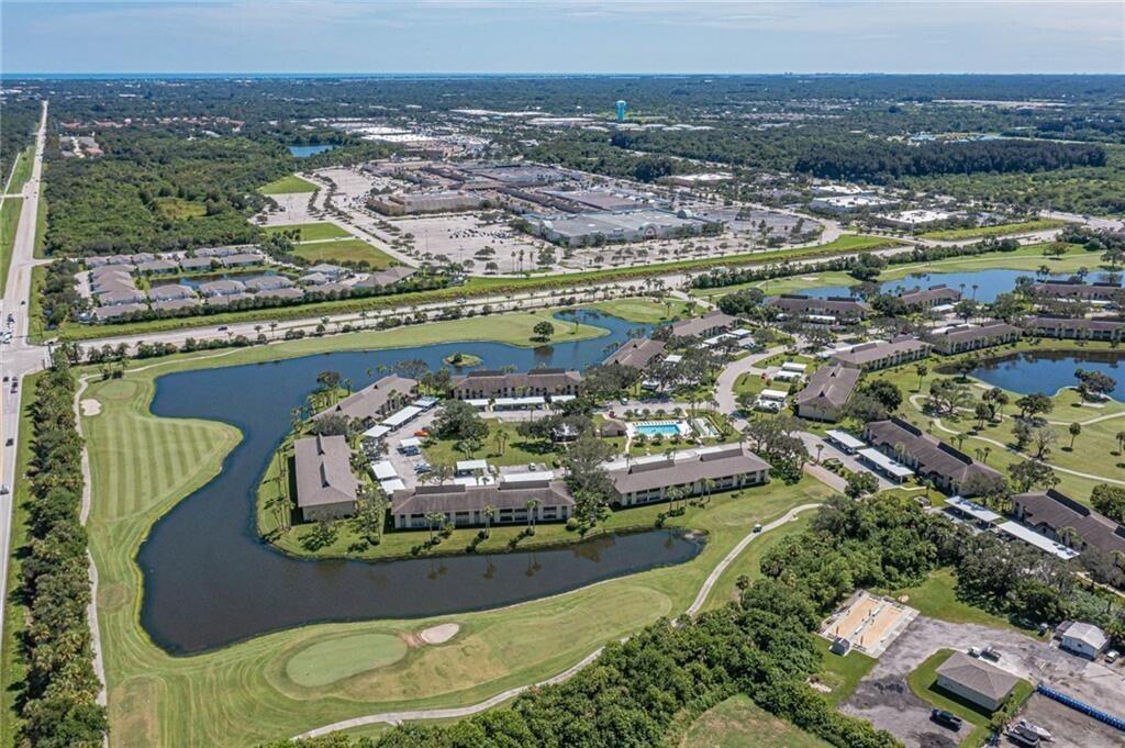 Aerial view of a residential complex surrounded by a golf course and a large lake — 32 Plantation Drive # 103, Vero Beach FL 32966, VERO BEACH, FL