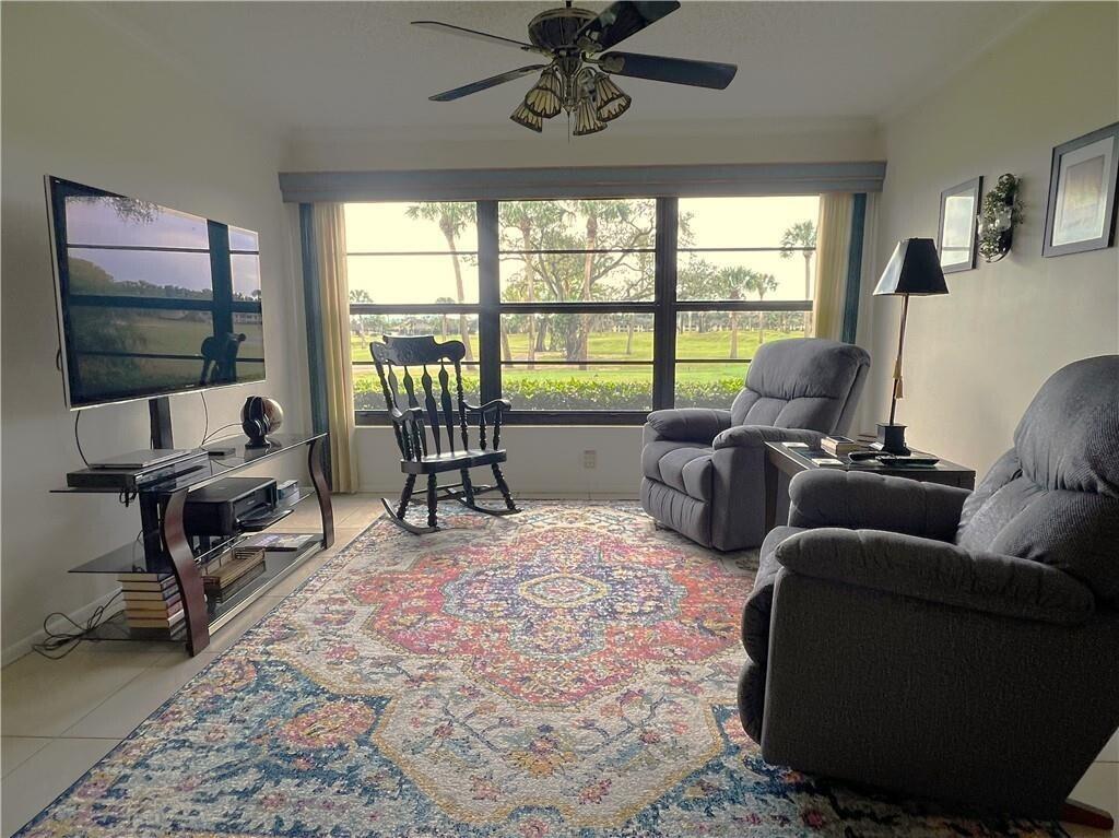 A living room features a large patterned rug, two recliners, a rocking chair, and window views — 32 Plantation Drive # 103, Vero Beach FL 32966, VERO BEACH, FL