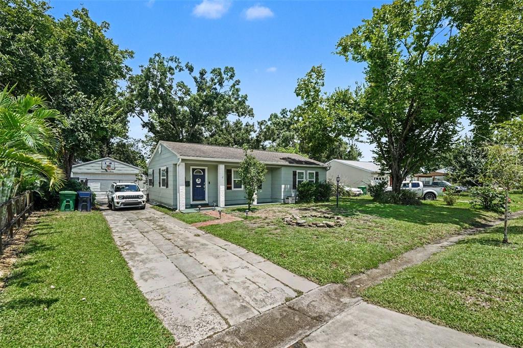 A light green single-story house with a driveway, front lawn, and a detached garage — 1509 W BARR DRIVE, TAMPA, FL