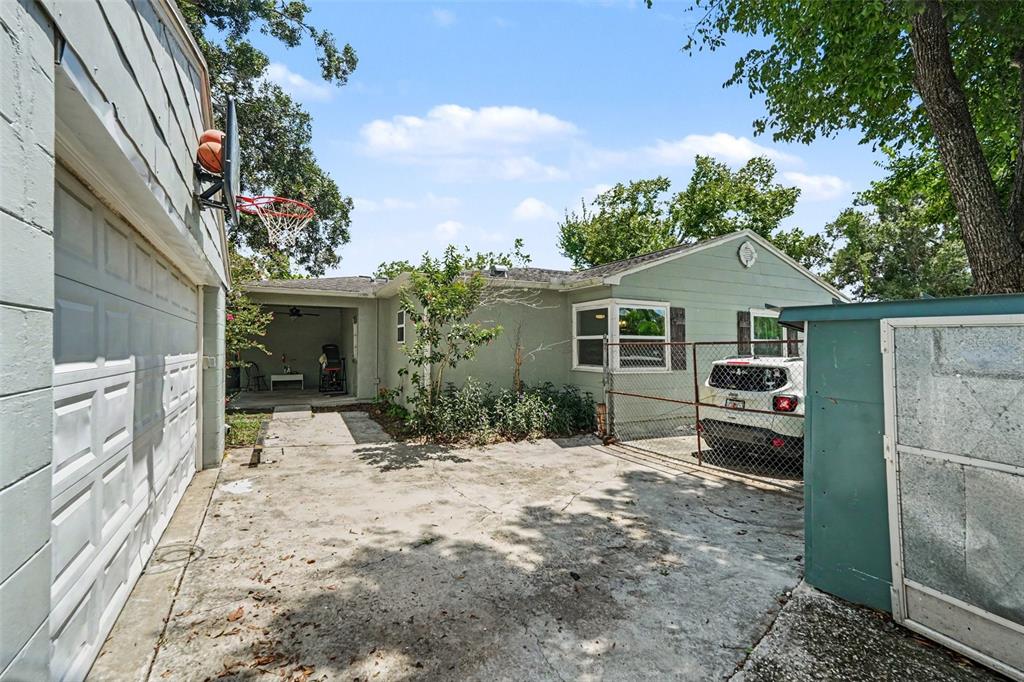 A concrete driveway leads to a house exterior with a garage and a chain-link fence — 1509 W BARR DRIVE, TAMPA, FL