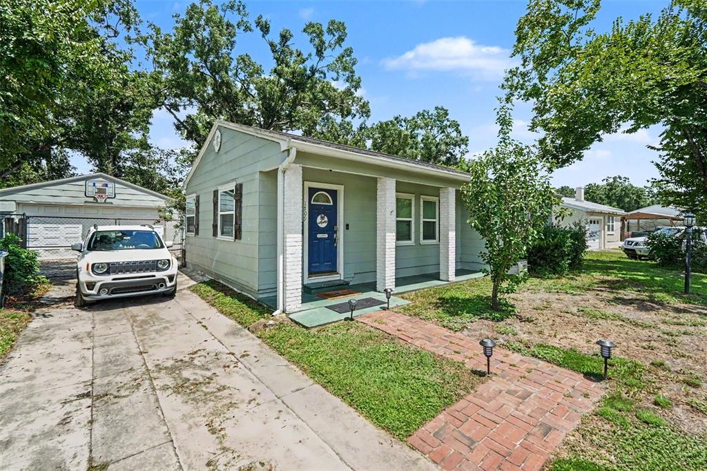 A light green single-story house with a blue front door, brick walkway, and detached garage — 1509 W BARR DRIVE, TAMPA, FL