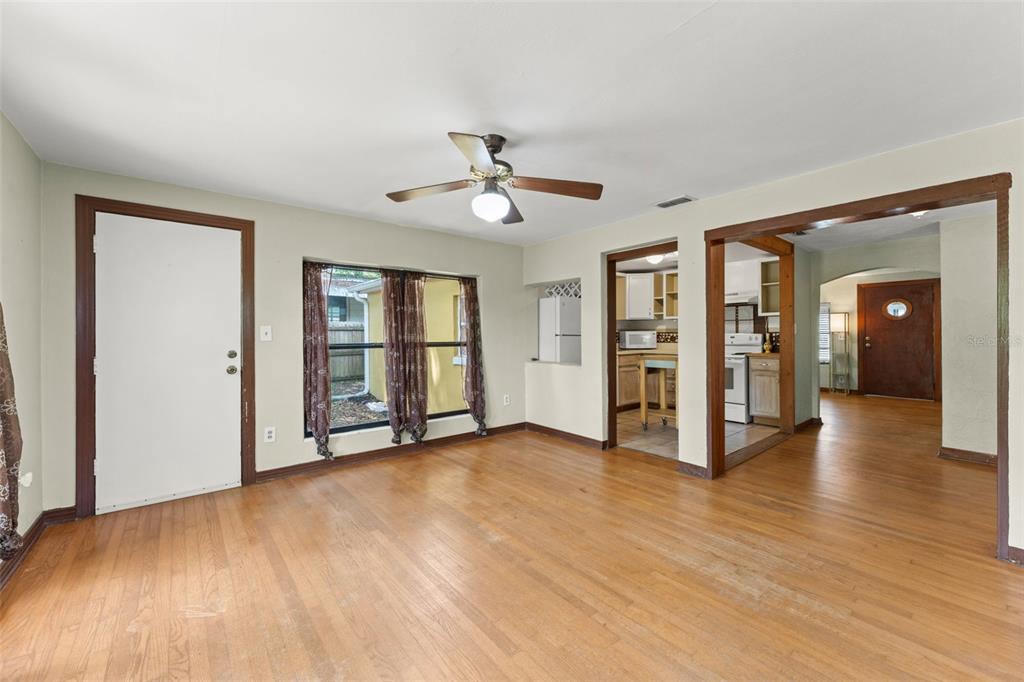 An empty living room with hardwood floors, a ceiling fan, and views into the kitchen — 440 CAMBRIDGE BOULEVARD, WINTER PARK, FL