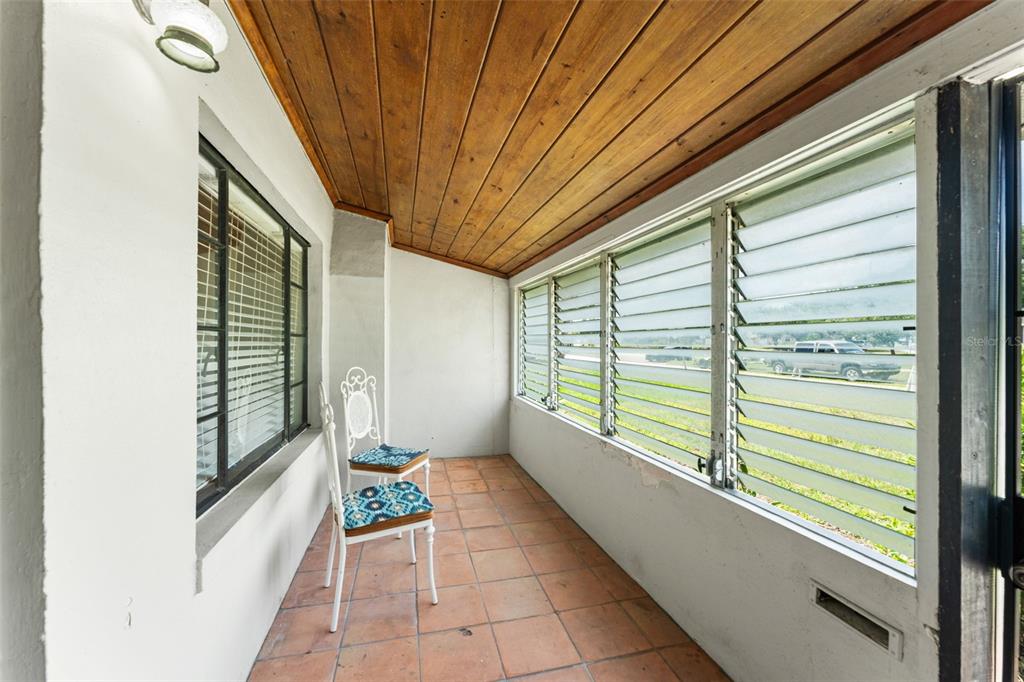 A sunroom features a wood-paneled ceiling, tiled floor, and walls of jalousie windows — 440 CAMBRIDGE BOULEVARD, WINTER PARK, FL
