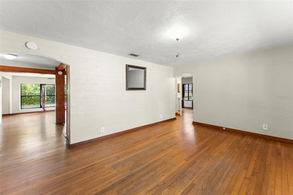 An empty room with hardwood floors, white walls, and an arched doorway leading to another room — 440 CAMBRIDGE BOULEVARD, WINTER PARK, FL