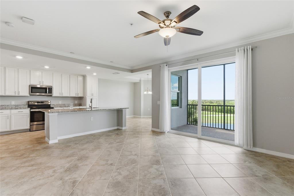 An open-concept kitchen and living area with tile floors, white cabinets, and a balcony view — 14081 HERITAGE LANDING BOULEVARD UNIT 237, PUNTA GORDA, FL