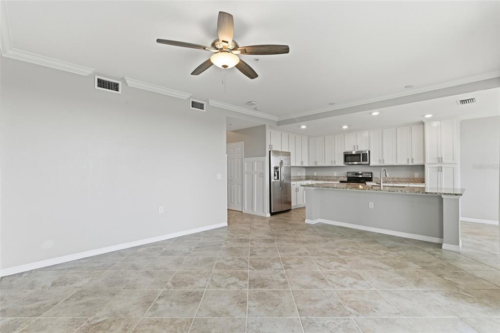 An open-concept kitchen with white cabinets and a breakfast bar overlooks a tiled living area — 14081 HERITAGE LANDING BOULEVARD UNIT 237, PUNTA GORDA, FL