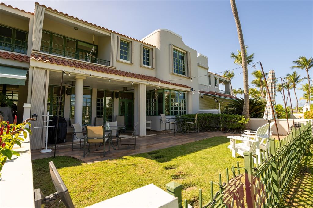 A two-story house with a patio, lawn, and green fence under a clear blue sky — Calle Arecife DORADO REEF UNIT P-65, DORADO, PR