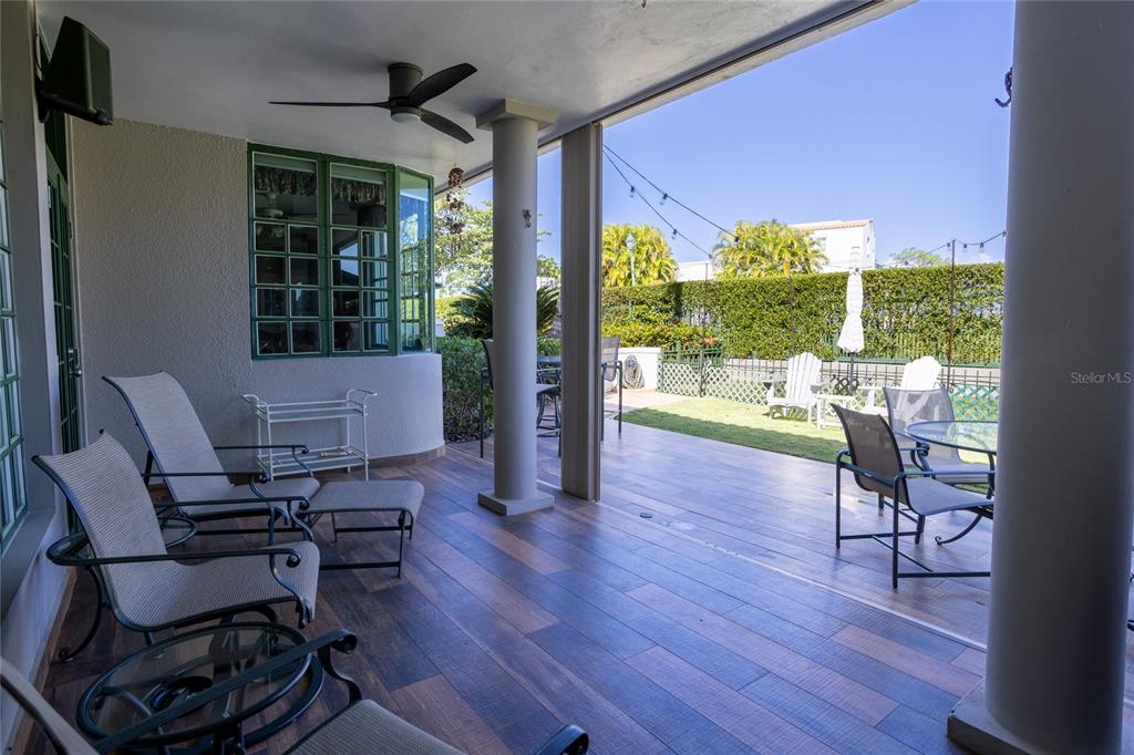 A covered patio features wood-look tile flooring, outdoor furniture, and a view of a backyard — Calle Arecife DORADO REEF UNIT P-65, DORADO, PR