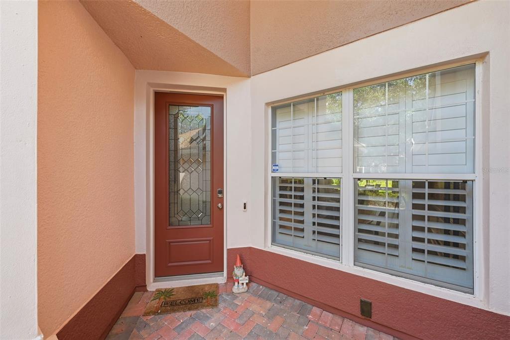 A red front door with a glass insert sits beside a window with white shutters — 8334 RIVERDALE LANE UNIT 10320, DAVENPORT, FL