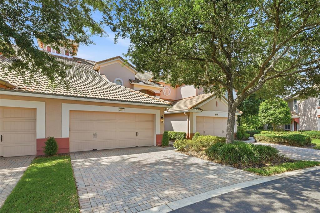 A two-story townhouse exterior with a two-car garage, tile roof, and a paved driveway — 8334 RIVERDALE LANE UNIT 10320, DAVENPORT, FL
