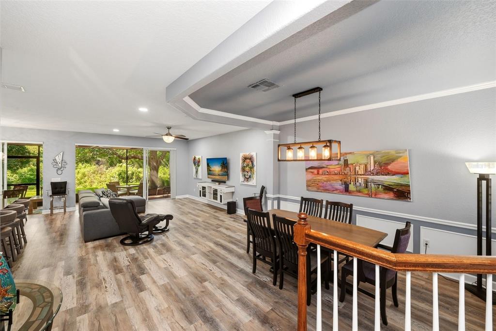 An open-concept living and dining area features wood-look flooring, a tray ceiling, and sliding doors — 8334 RIVERDALE LANE UNIT 10320, DAVENPORT, FL