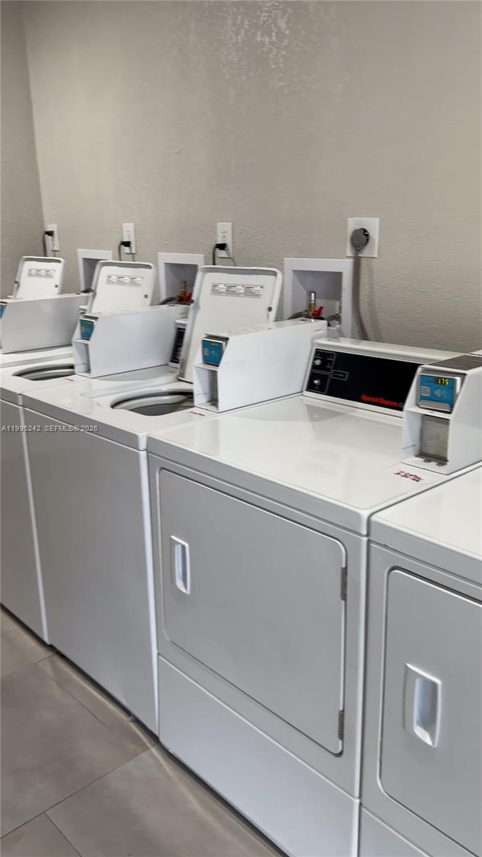 A row of white coin-operated washing machines and dryers sits against a plain wall — 1225 W 35th St # 2A, Hialeah FL 33012, HIALEAH, FL