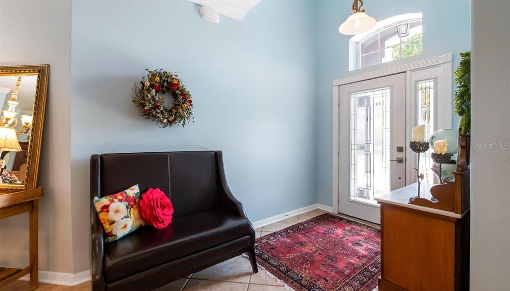An entryway features a dark leather bench, a red patterned rug, and a front door — 4010 HAMMERSMITH DRIVE, CLERMONT, FL
