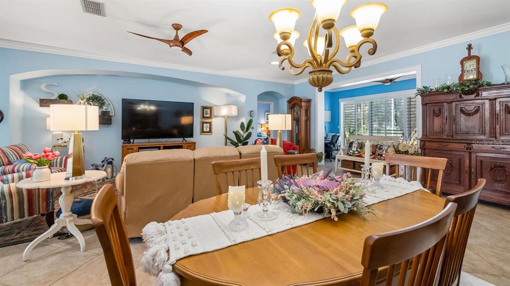 A dining area with a wooden table sits in the foreground of a living room — 4010 HAMMERSMITH DRIVE, CLERMONT, FL