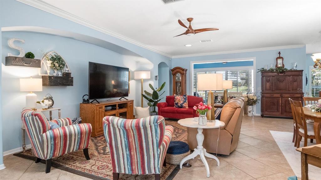 A living room features light blue walls, tiled floors, striped armchairs, and a red sofa — 4010 HAMMERSMITH DRIVE, CLERMONT, FL