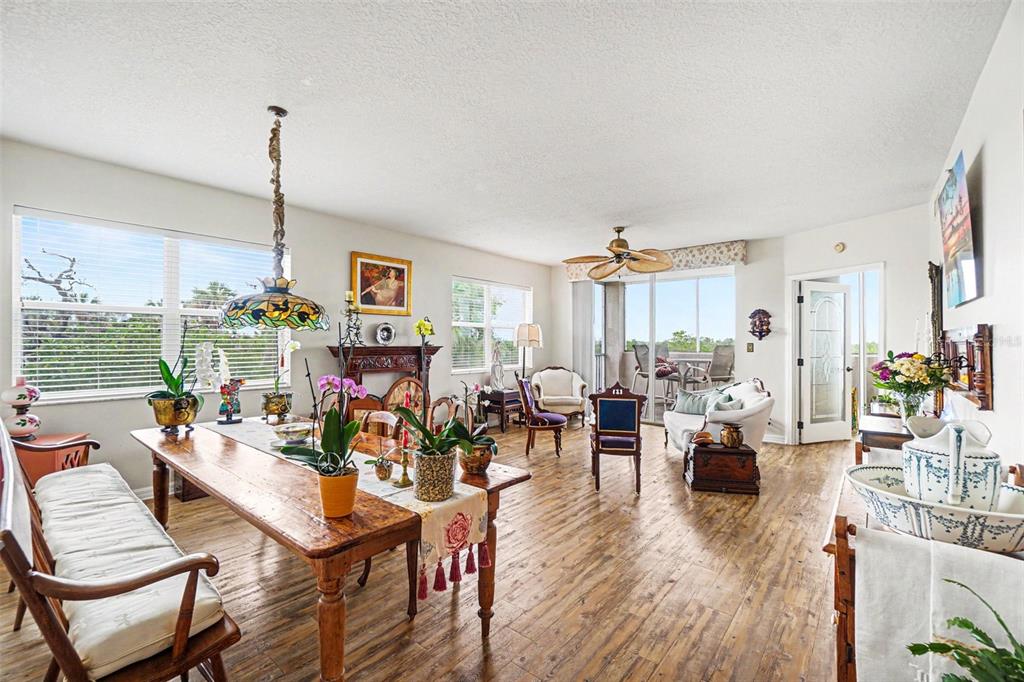 A dining and living area features wood-look flooring, a wooden table, and a balcony view — 2625 TERRA CEIA BAY BOULEVARD UNIT 201, PALMETTO, FL