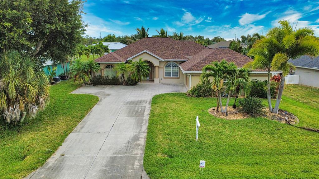 A single-story house with a brown shingled roof, concrete driveway, and palm trees in front — 138 BROADMOOR LANE, ROTONDA WEST, FL