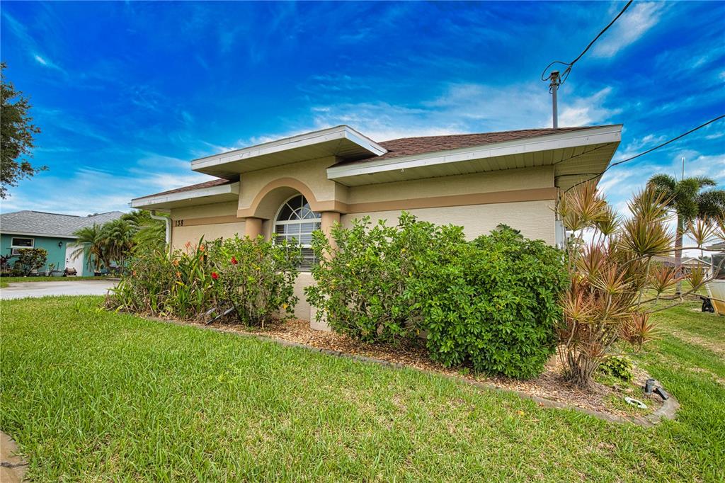 A single-story house with a beige stucco exterior, a brown roof, and front landscaping — 138 BROADMOOR LANE, ROTONDA WEST, FL